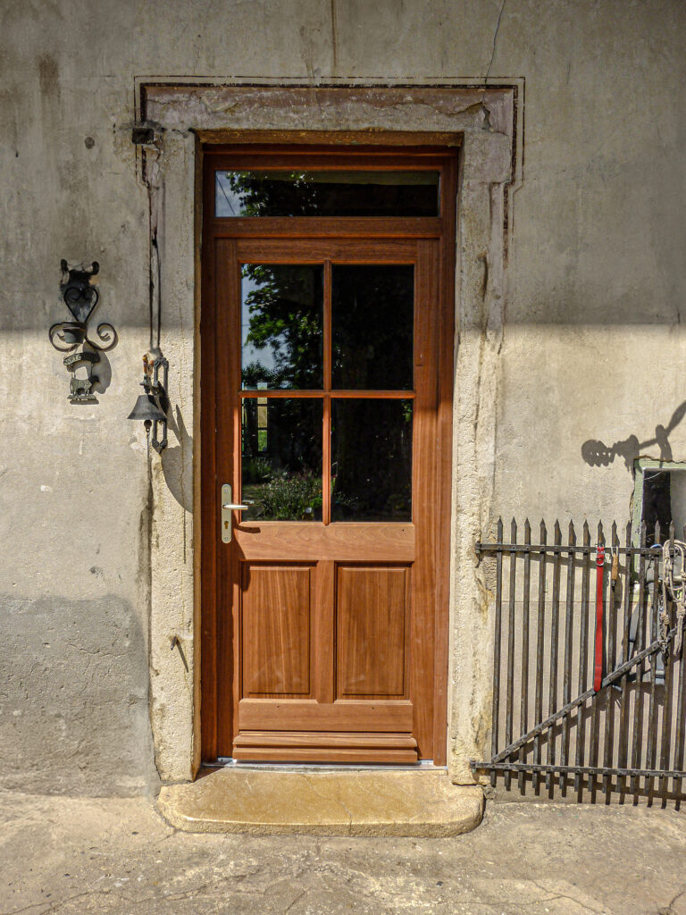 Porte d'entrée en bois exotique avec petits bois et panneaux plates-bandes, style traditionnel.