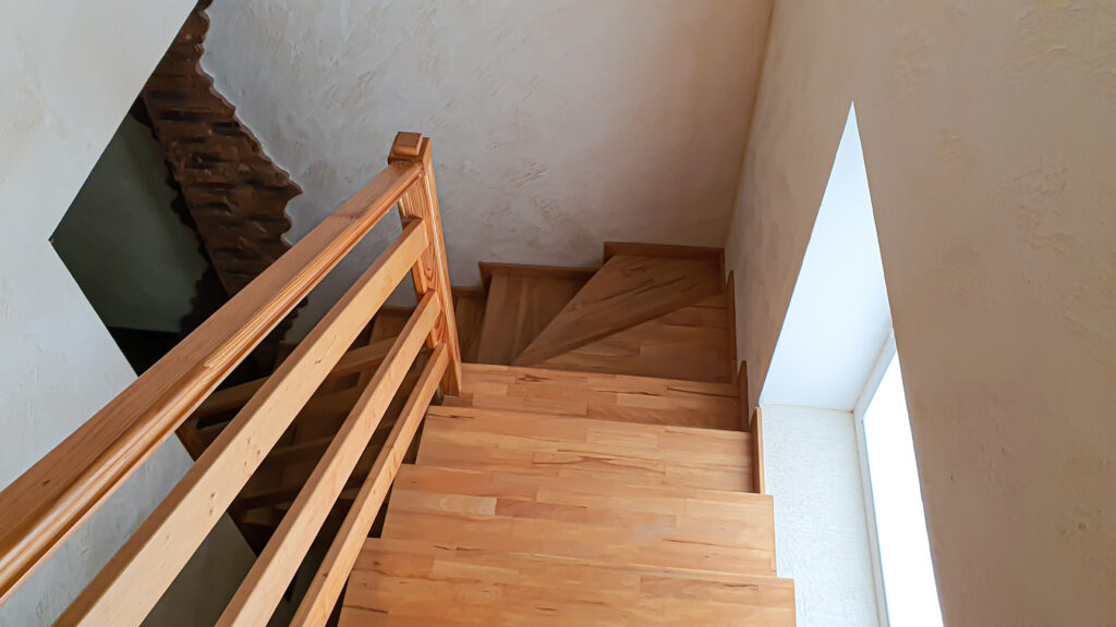 Escalier quart tournant simple en bois clair avec des marches en éventail.